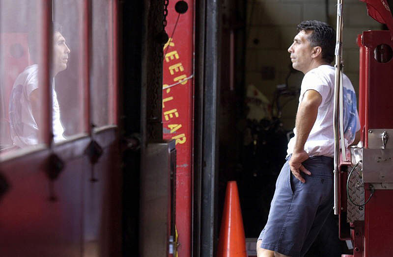 Firefighter Vincent De Forte of Ladder 15 looks pensively out a window at the South Street firehouse, home to Engine 4 and Ladder 15. The station was rearranged to make temporary quarters for Ladder 10 until the Ten House fire station on Liberty Street is rebuilt.  Photo by Mike De Sisti 8/7/02 © 2002 Appleton Post-Crescent