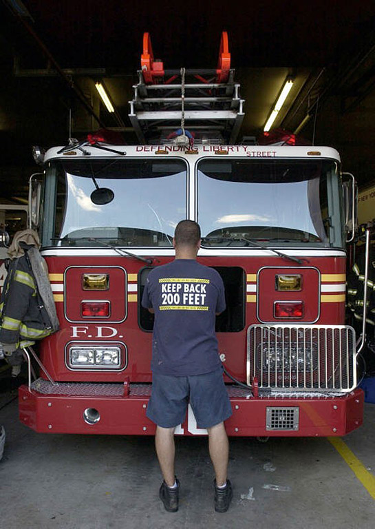 Kevin Ekberg of Ladder 10 repairs a loose grille on the front of the Ladder 10 truck at the company's temporary South Street firehouse. The truck, built at Seagrave Fire Apparatus in Clintonville, has sustained a few dings during the past six months but is otherwise in near perfect condition.  Photo by Mike De Sisti 8/9/02 © 2002 Appleton Post-Crescent